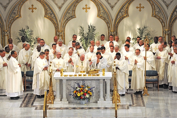 Flanked by the four new new priests, Father Gerard Skrzynski, Father Peter Santandreu, Father Paul Stanislaw Cygan, Father Peter Nsa Bassey and clergy from area parishes, Bishop Richard J. Malone blesses the gifts during a Mass at St. Joseph Cathedral where the four men were ordained into the priesthood. (Dan Cappellazzo/Staff Photographer)
